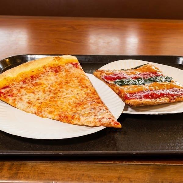 Two pizza slices, one cheese and one tricolor, on paper plates on a black tray.