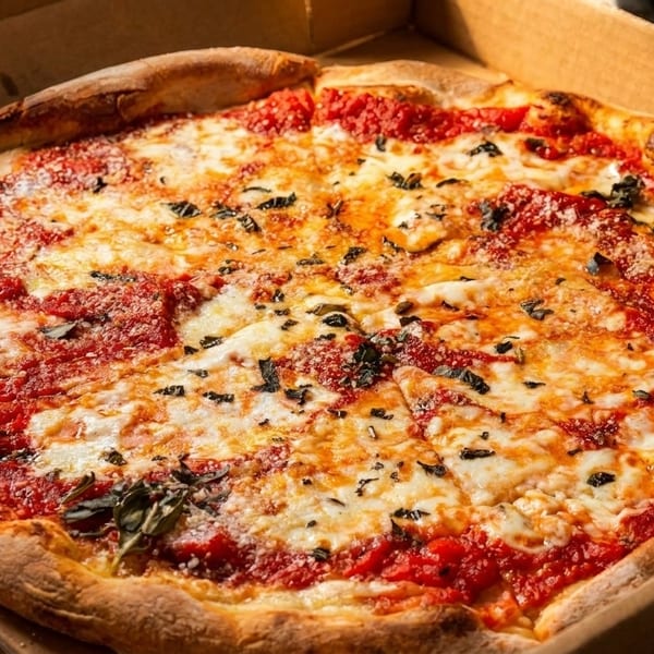 Freshly baked Margherita pizza with melted mozzarella, rich tomato sauce, and basil in a cardboard box.
